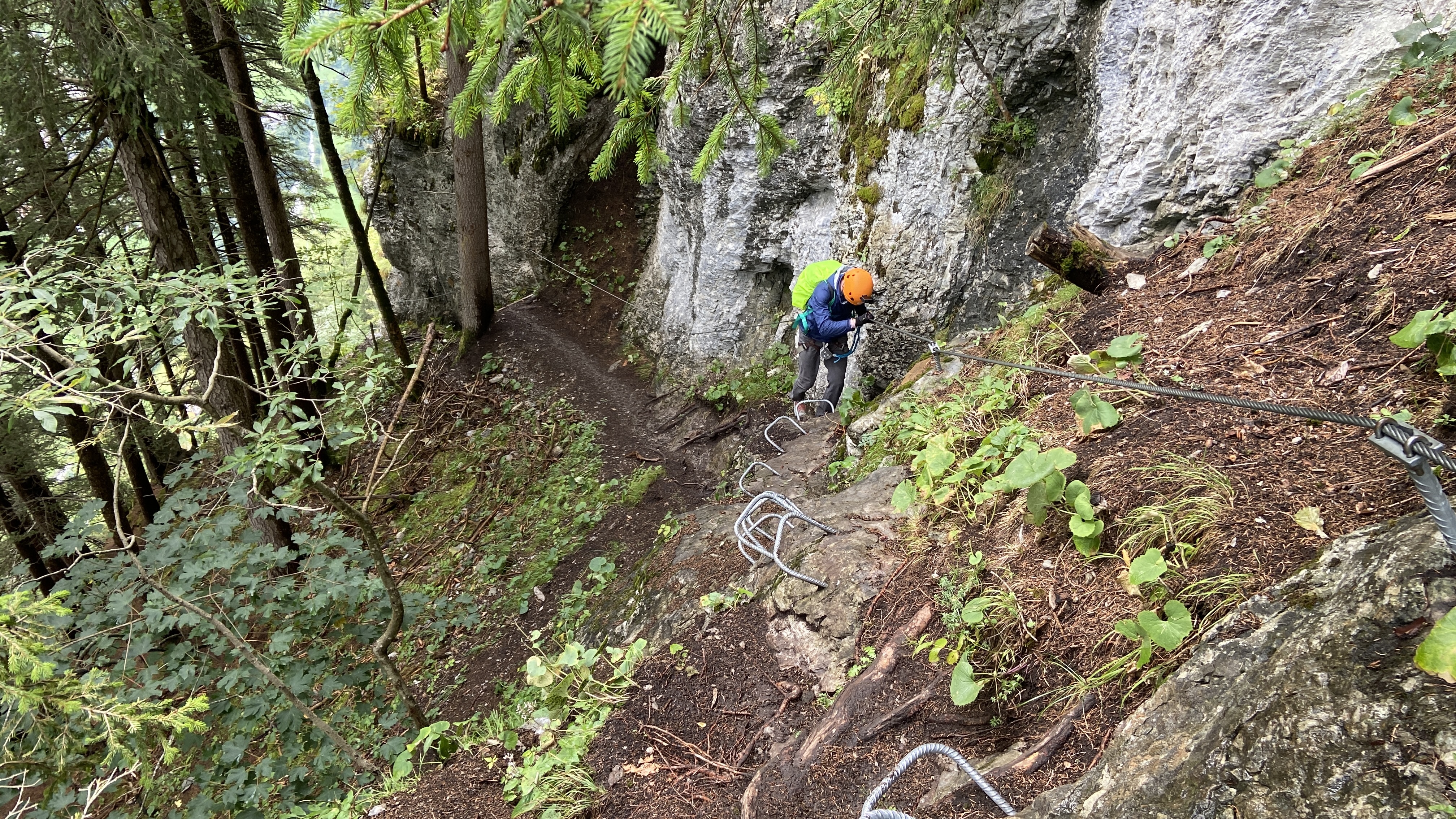 Brett climbing down metal runs in the forest on the via ferrata murren switzerland