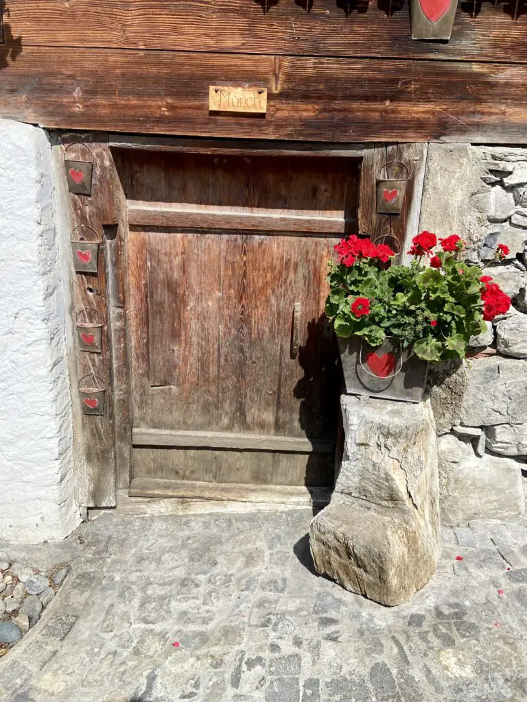 wooden door with red flowers on a rock on brunngasse brienz switzerland