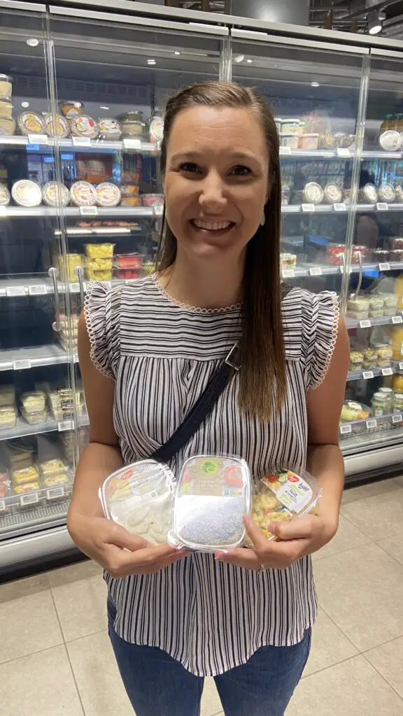 jana holding a pasta salad, lentil salad, and potato salad from migros grocery store in switzerland