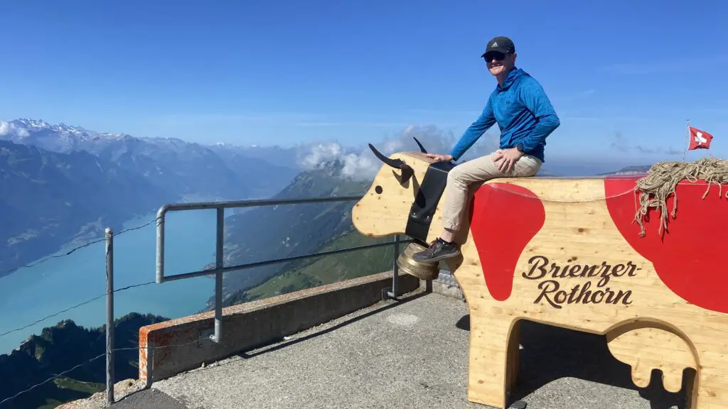 brett sitting on a trauffer wooden cow at brienzer rothorn