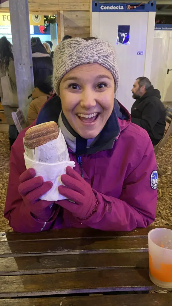 jana from aplins in the alps eating a chimney cake at christmas market in switzerland lausanne