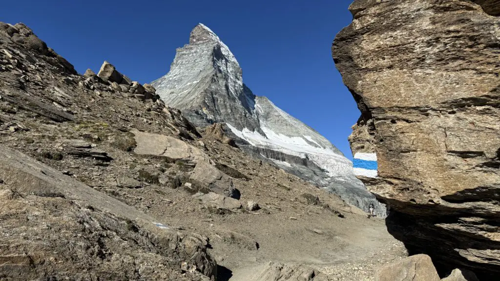 Blue and white trail sign in zermatt pointing the way to the base of the matterhorn and the hornli hut